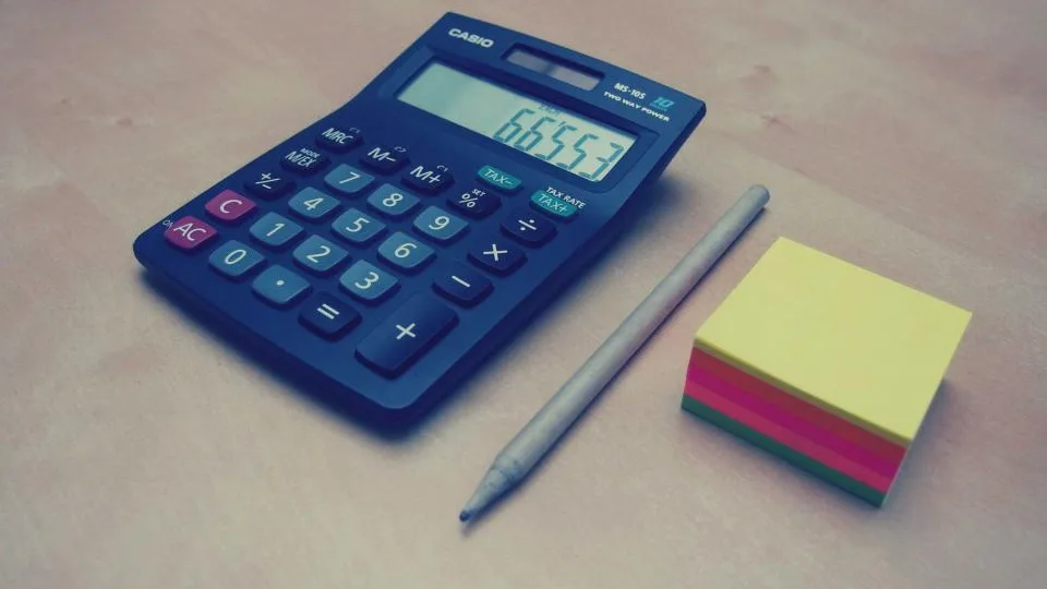 Calculadora azul, lápis e blocos de notas adesivas sobre a mesa