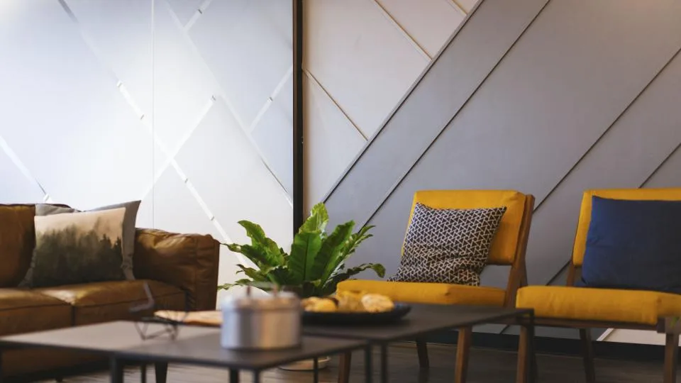 Sala de estar com sofá de couro, poltronas amarelas, mesa de centro e planta